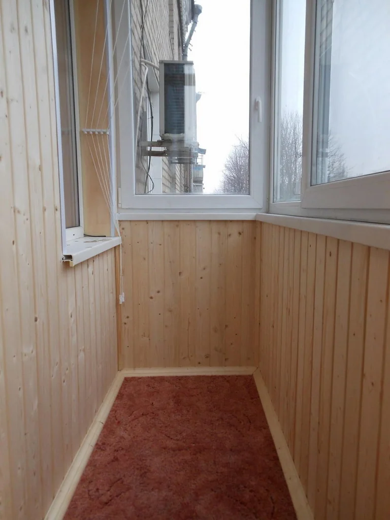 Світла обшивка стін і коричневе покриття підлоги на балконі