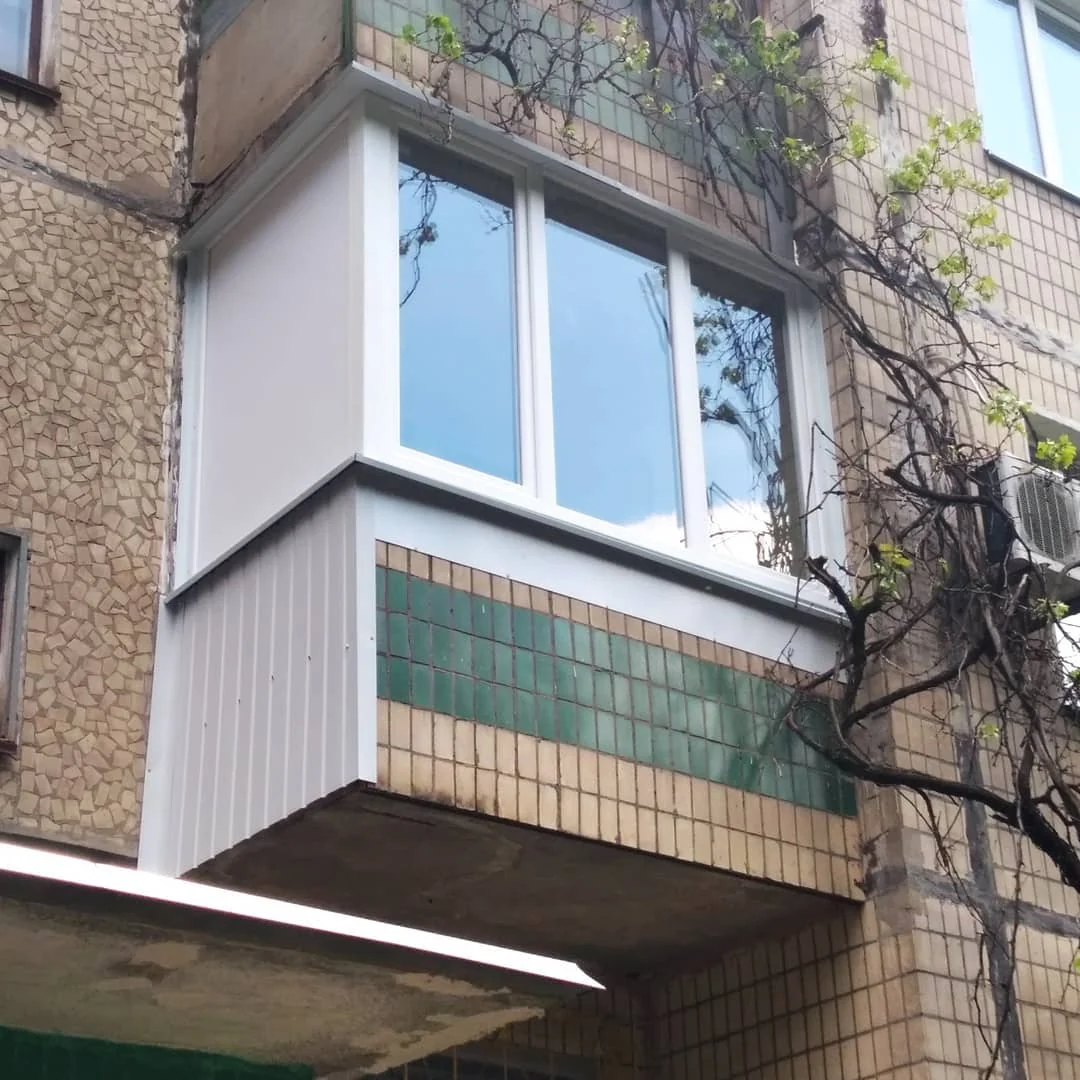 Кутовий балкон зі світлими рамами й різним оздобленням нижньої частини