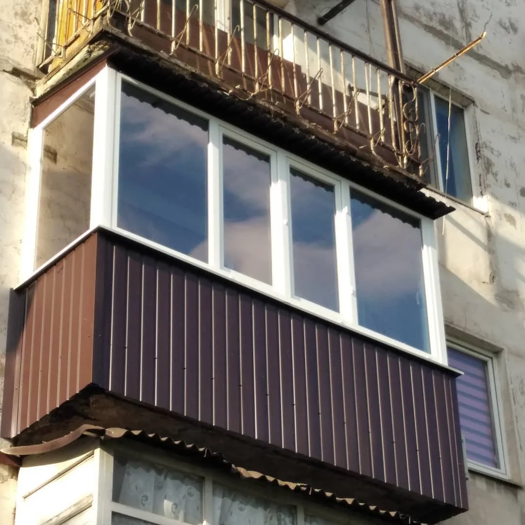 Балкон із коричневою обшивкою та білими рамами