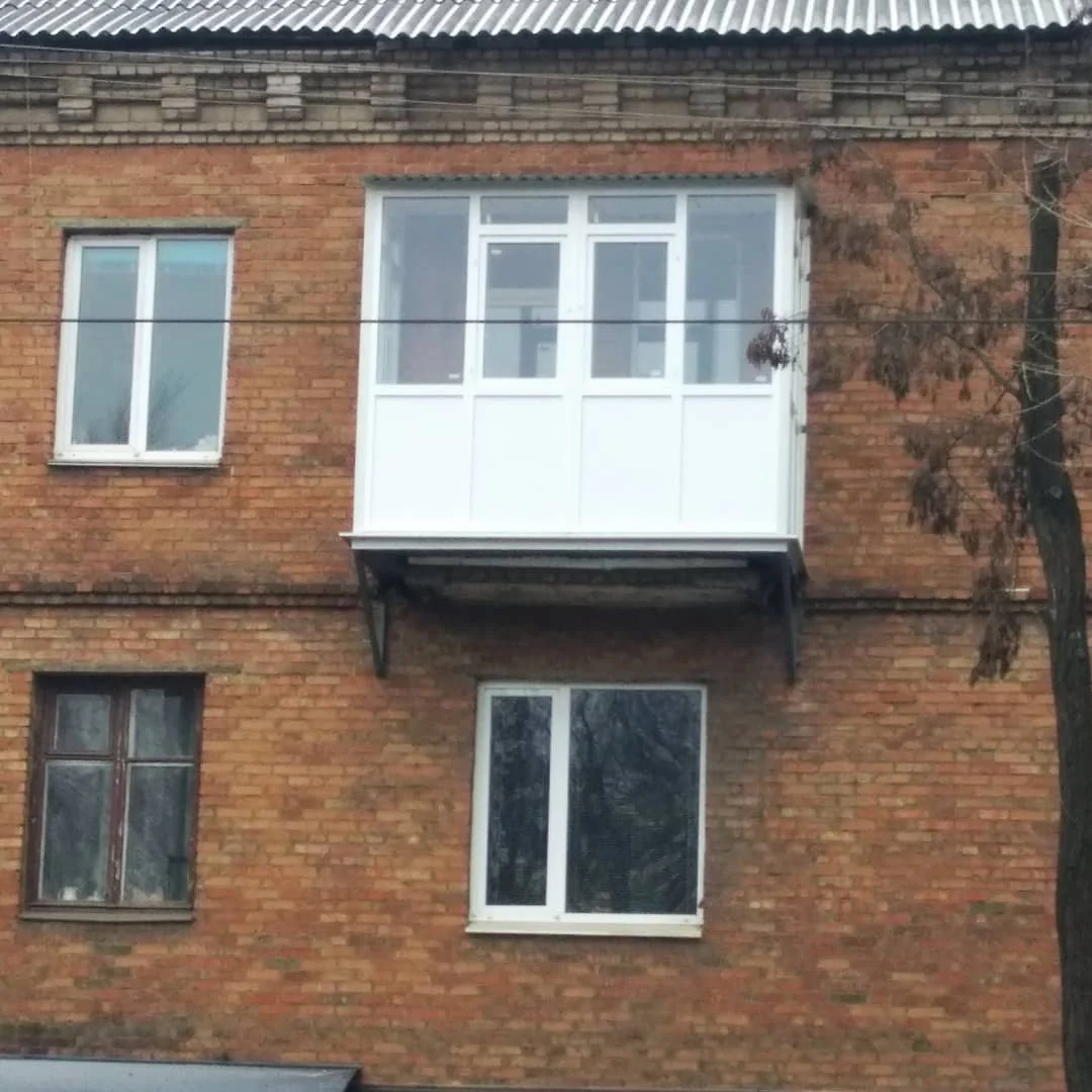 Балкон зі світлою обшивкою на цегляному фасаді