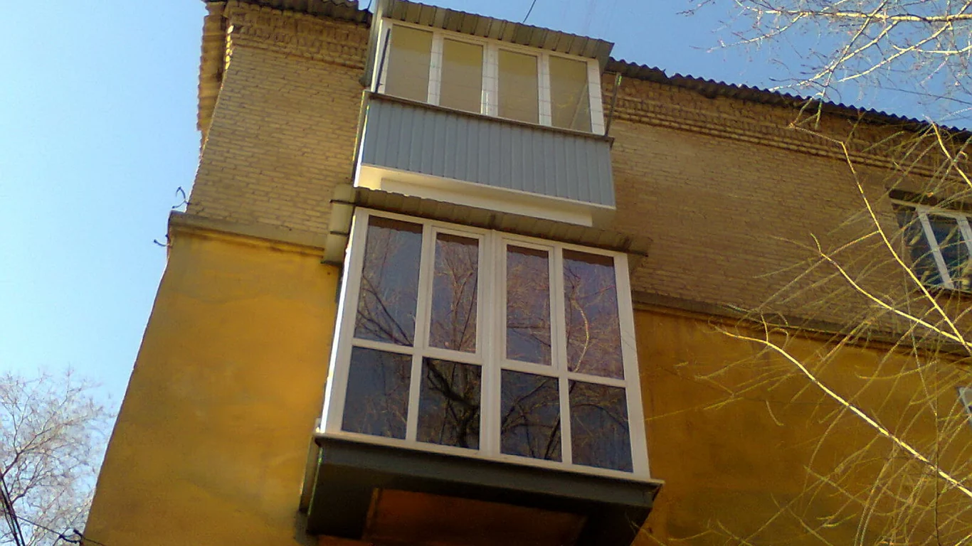 Французький балкон із білими рамами на жовтому фасаді
