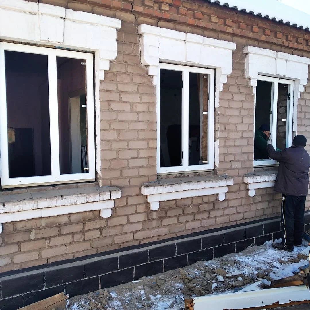 Ряд білих вікон на цегляному фасаді