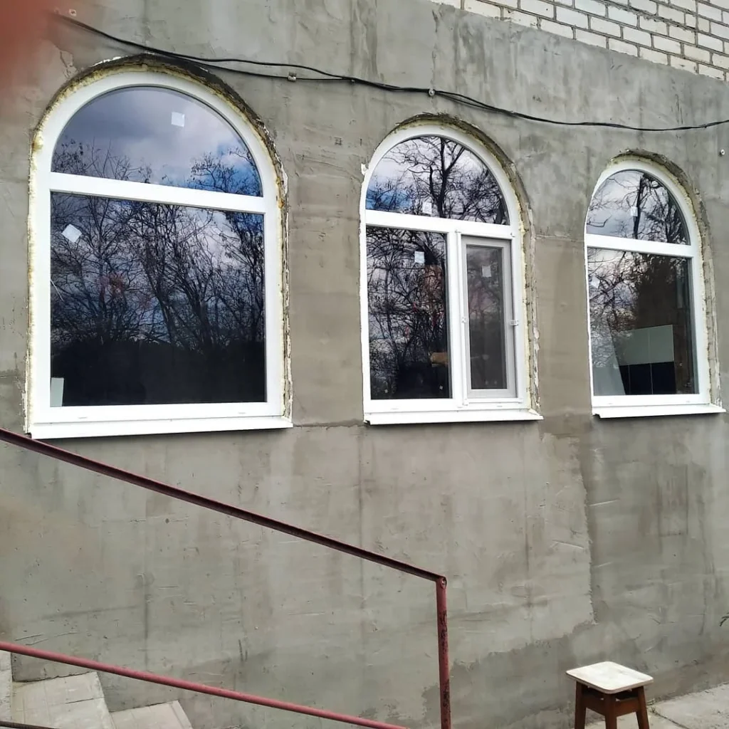 Арочне вікно та сусідній проріз на світлому фасаді