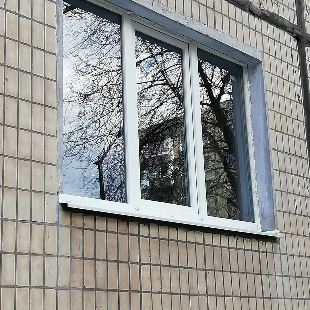 Біле вікно на фасаді, облицьованому плиткою