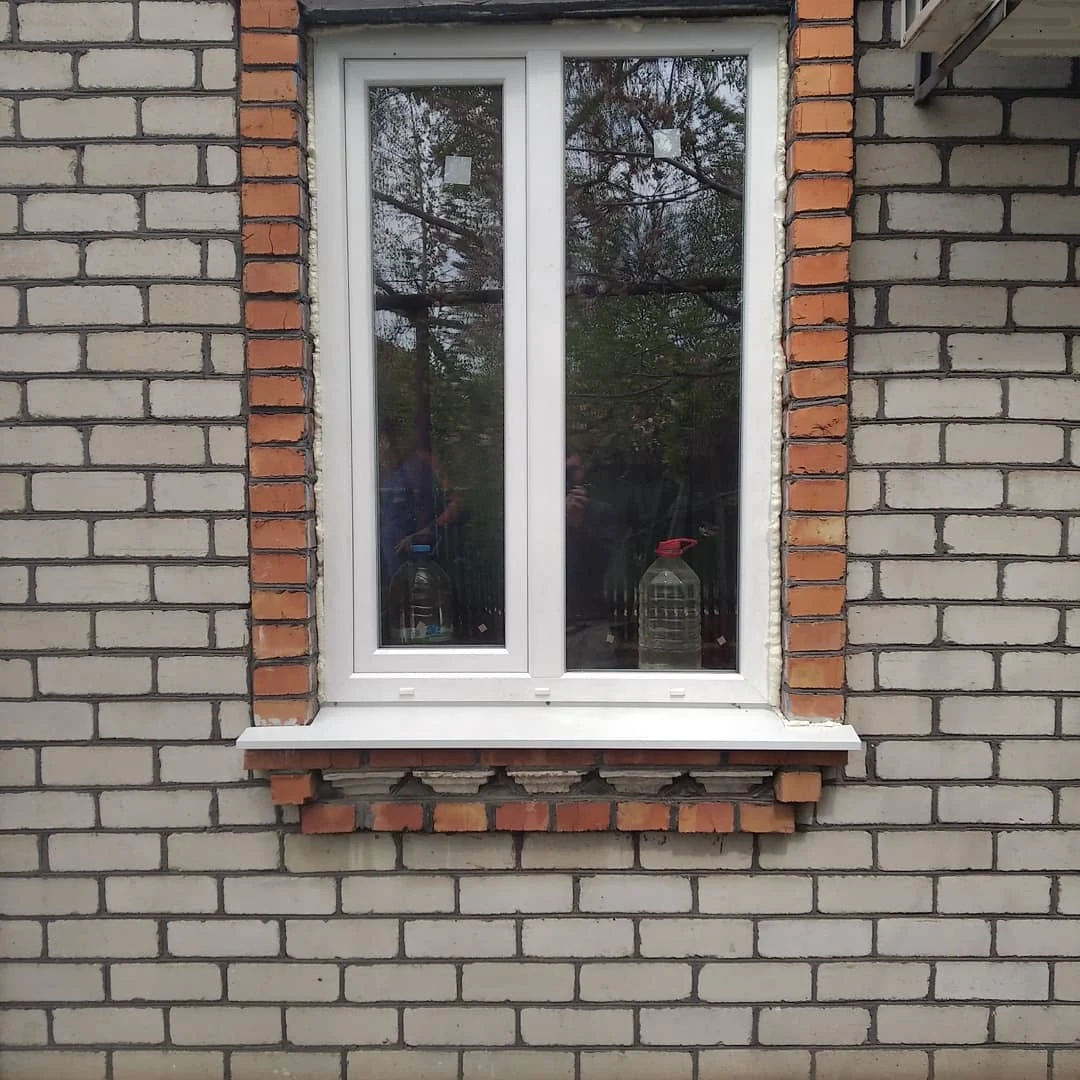 Біле вікно в цегляному прорізі з оформленим обрамленням